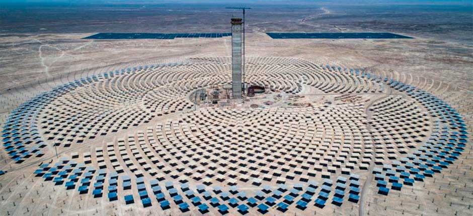 usina solar térmica com uma grande torre no centro e ao lado vários espelhos circundantes, heliostatos