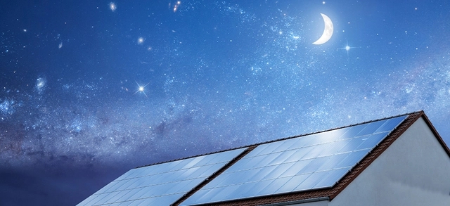 placas de energia solar fotovoltaica sob uma casa durante a noite e ao fundo a lua junto às estrelas