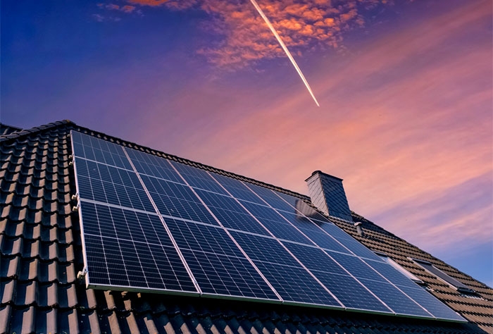 placas de energia solar instaladas sob o telhado de uma residência e ao fundo um céu com nuvens